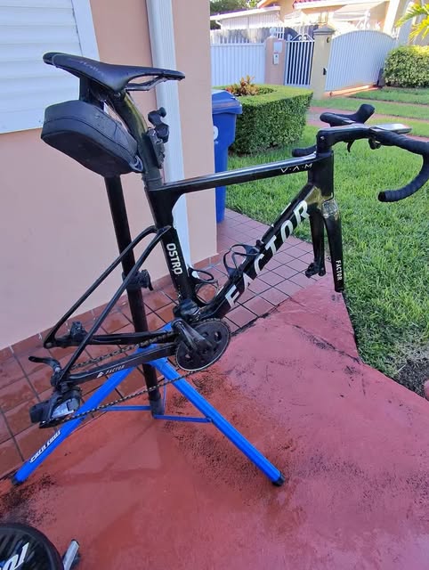 Factor Ostro VAM road bike on a repair stand in a driveway