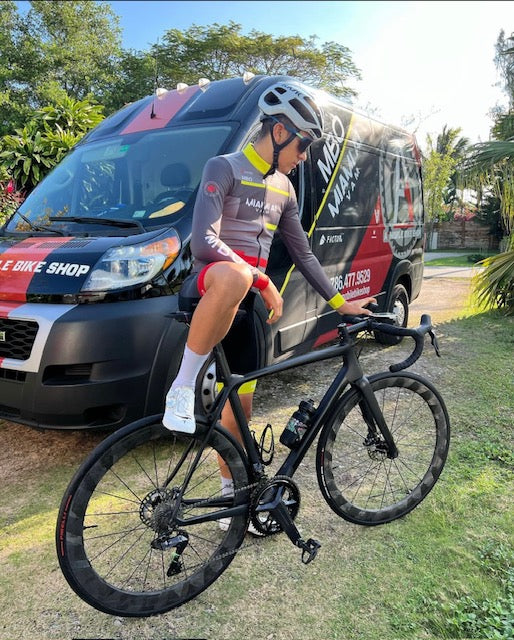 A rider in Miami A1 team kit next to the black A1 Mobile Bike Shop van